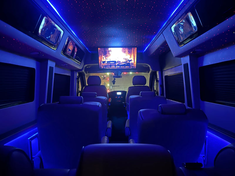 Interior of a luxury rv rental with vibrant blue lighting, a starry ceiling, and a screen displaying a fireplace. — photo 13