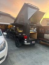 This black Tacoma overland pickup, fitted with an Alu-Cab camper & RTT, could be a great RV rental for unique adventures.