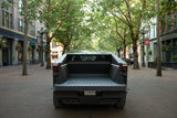 Rear view of a Tesla Cybertruck with open bed, parked on a brick street. A modern EV for travel needs beyond typical rv rental.