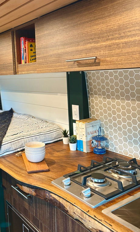 Explore this custom RV rental interior featuring a modern kitchen, comfy bed, and unique live-edge wood.