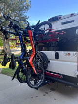 Two folding e-bikes on a hitch-mounted rack at the back of a Winnebago Solis RV, perfect for your next rv rental adventure.