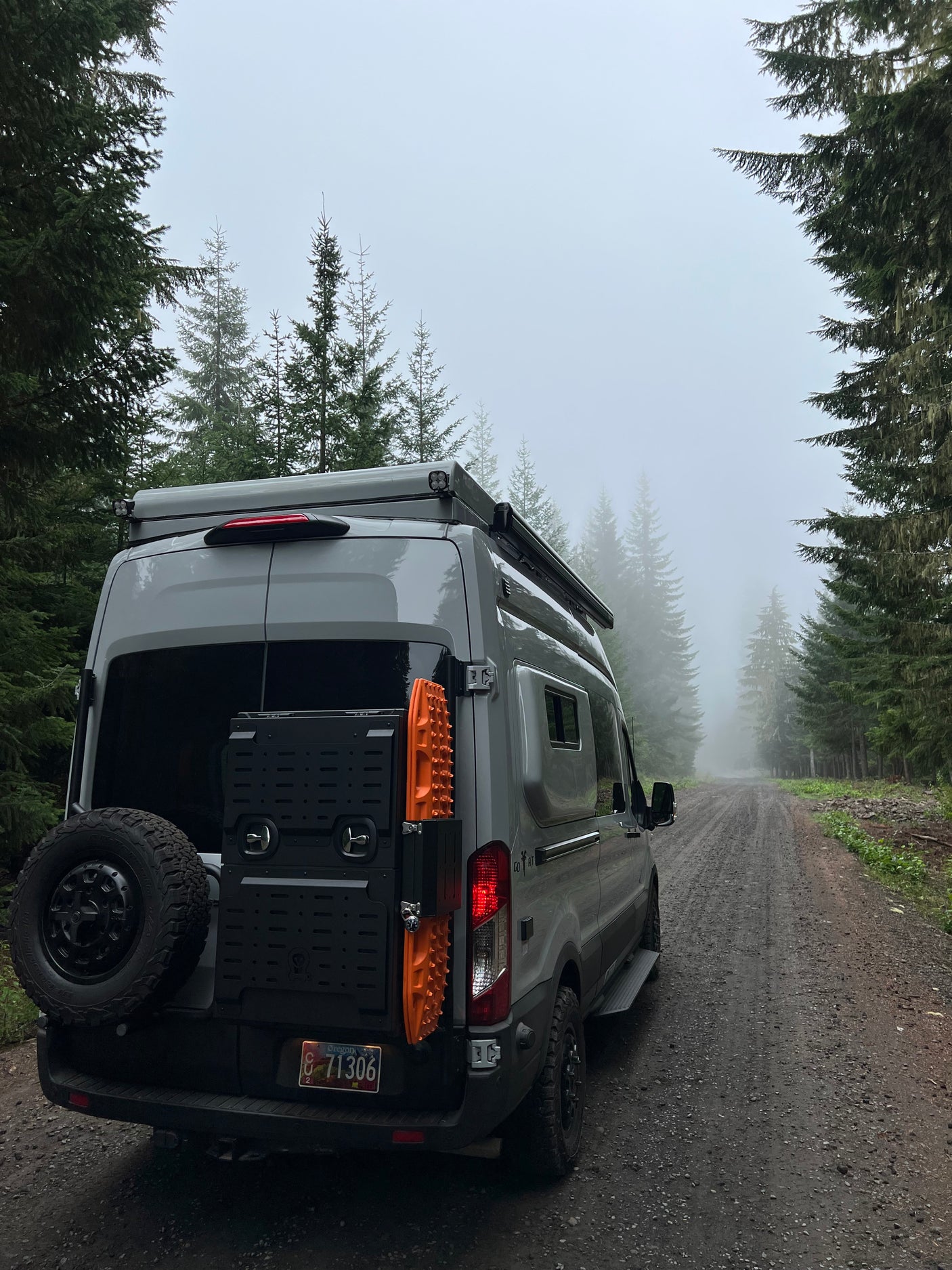 Gray RV rental parked on a foggy forest road, ready for off-grid camping adventures and scenic travel.