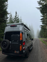 Gray RV rental parked on a foggy forest road, ready for off-grid camping adventures and scenic travel.