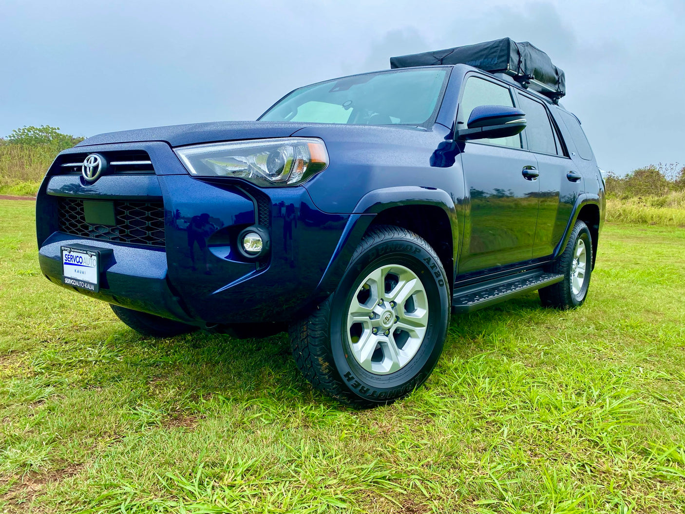 Dark blue Toyota 4Runner SUV with rooftop tent on grass, perfect for your next outdoor rv rental adventure.