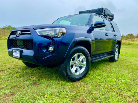 Dark blue Toyota 4Runner SUV with rooftop tent on grass, perfect for your next outdoor rv rental adventure.
