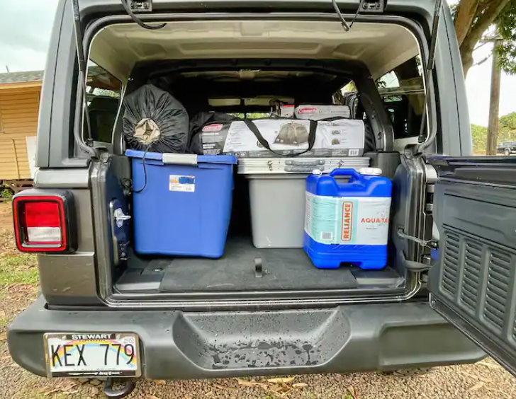 Inside a packed Jeep: blue tote, water jug, and camping gear for a road trip or RV rental adventure. Ready to go! — photo 6