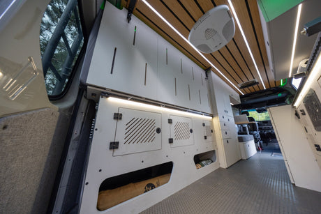 Modern campervan rv rental interior: custom storage, wood-slat ceiling with LED lights, and durable flooring for comfortable travel.