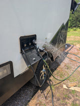 RV rental's outdoor shower spraying water on the side of the trailer, perfect for rinsing off gear and staying clean.