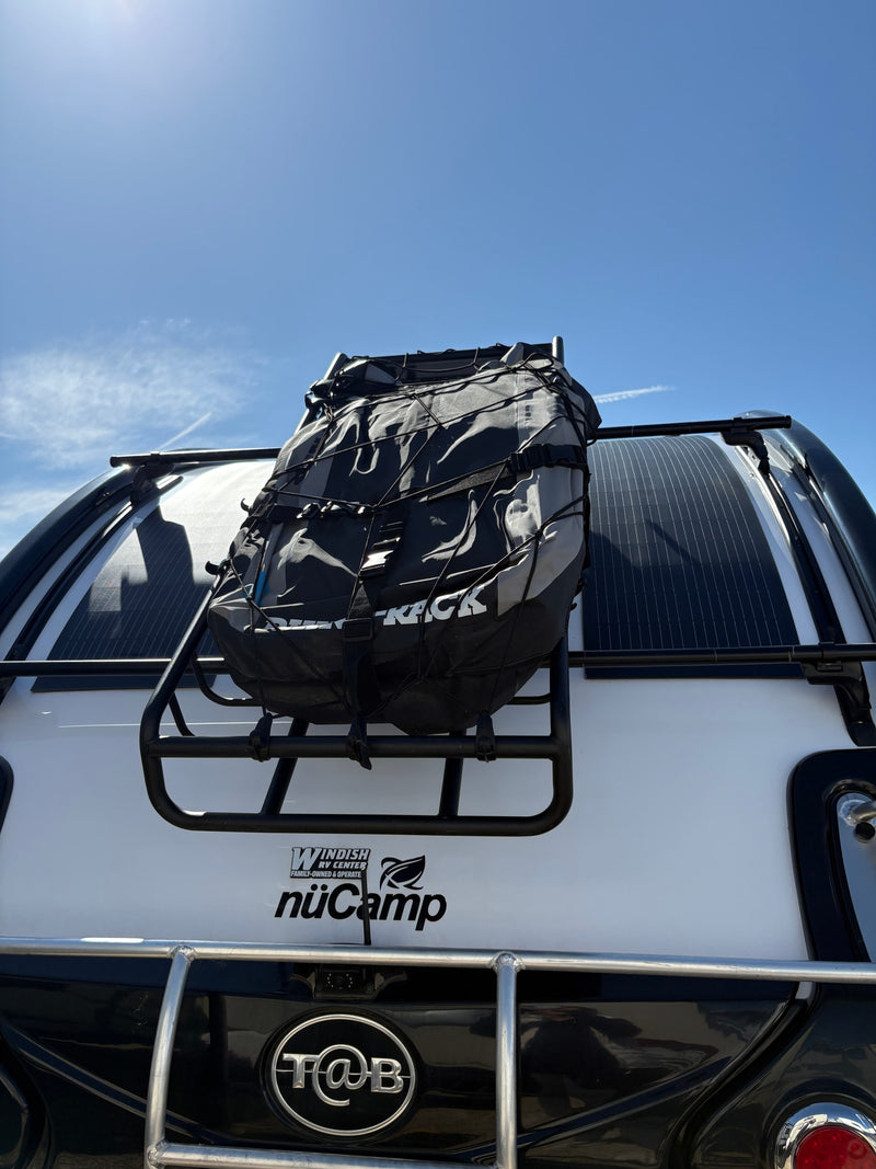 Back of a NuCamp T@B rv rental camper: cargo bag on a rack, solar panels on top, under a bright blue sky. — photo 9