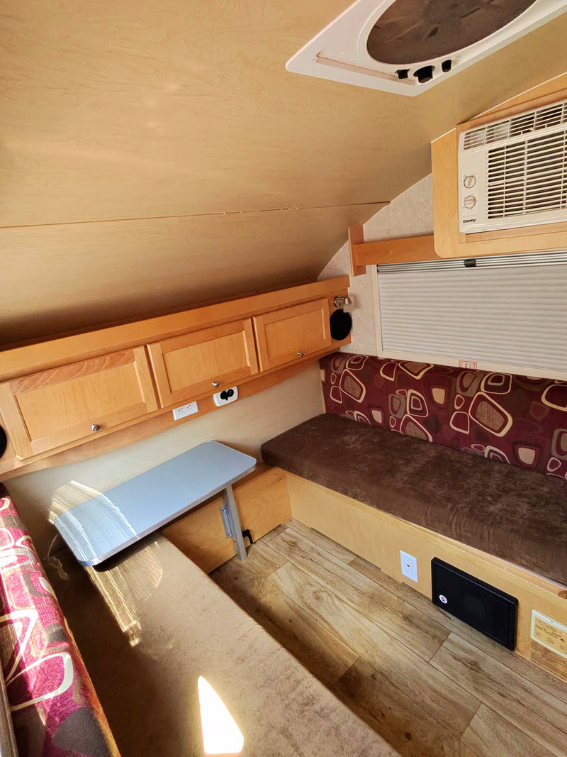 Cozy RV rental interior with a dinette, wood-look floor, overhead storage, AC, and roof vent. — photo 5