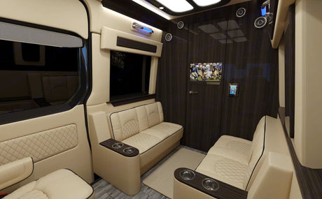 Luxury RV rental interior featuring plush beige seating, TV showing football, and a wall tablet control panel.