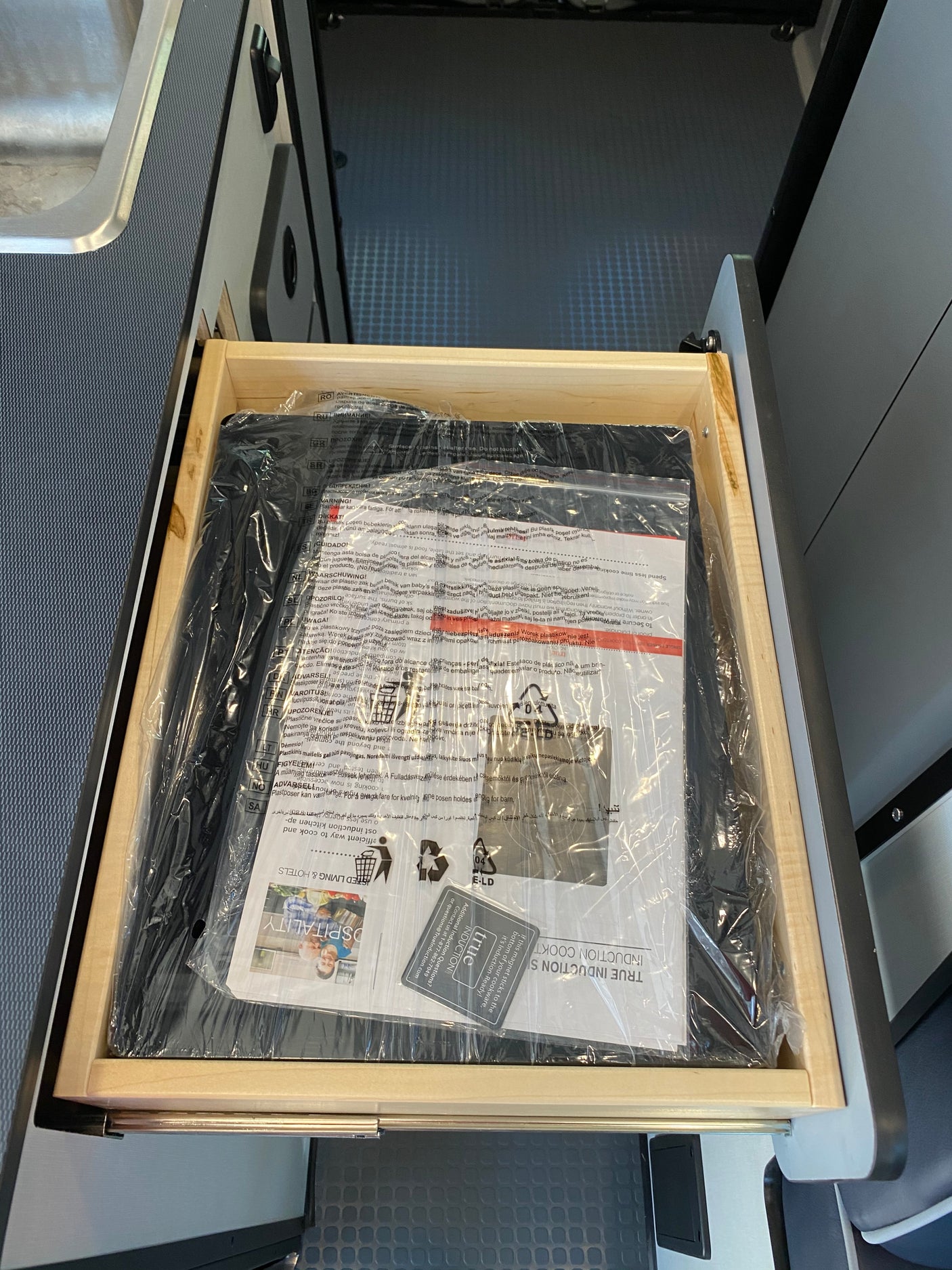 New True Induction cooktop and manuals in an RV rental drawer, ready for compact cooking adventures.