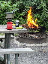 Enjoying a campsite meal prep with a roaring campfire and portable stove. Perfect for your next RV rental adventure!