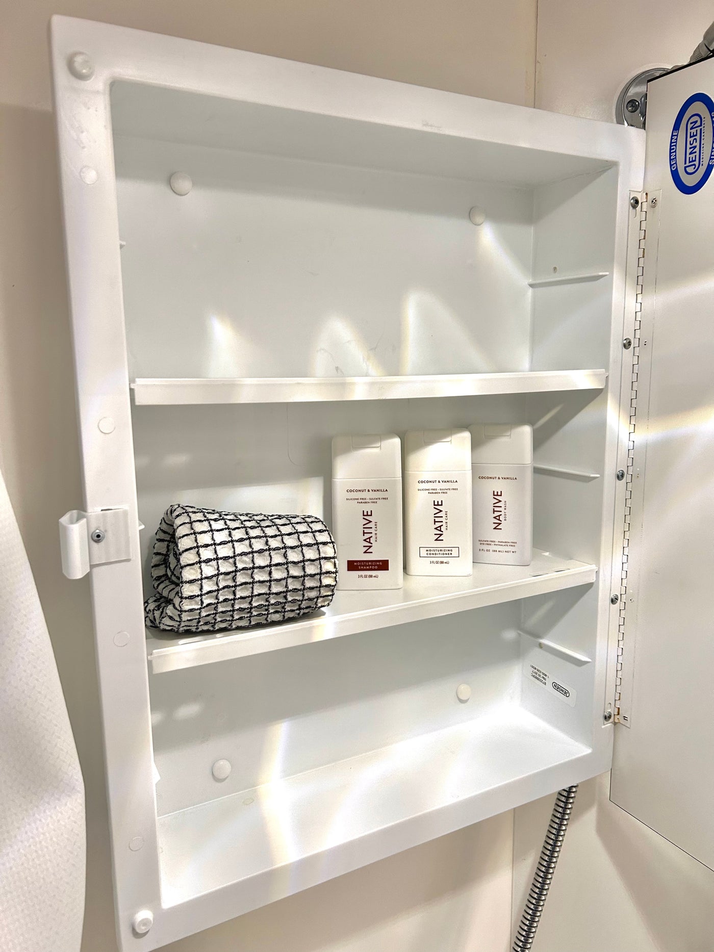 Compact white medicine cabinet in an RV rental, stocked with travel-sized Native brand toiletries & a towel. Jensen cabinet. — photo 15