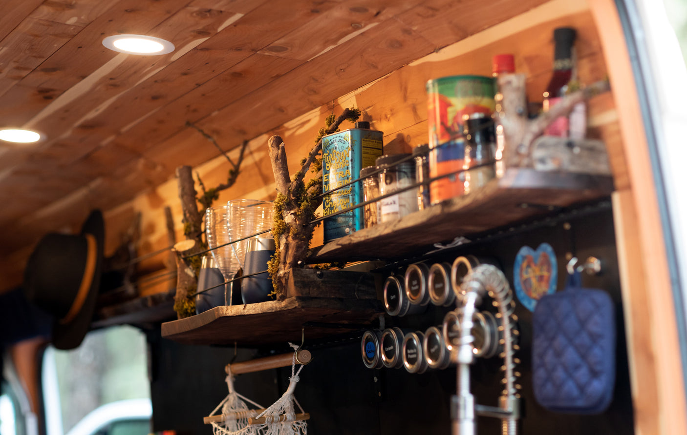 Detailed RV rental interior: custom wooden shelves, recessed lights, and magnetic spice rack with olive oil. Perfect for van life storage.