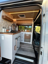 Explore this modern rv rental interior with a built-in kitchen, sleek wood accents, and window views for your next adventure.