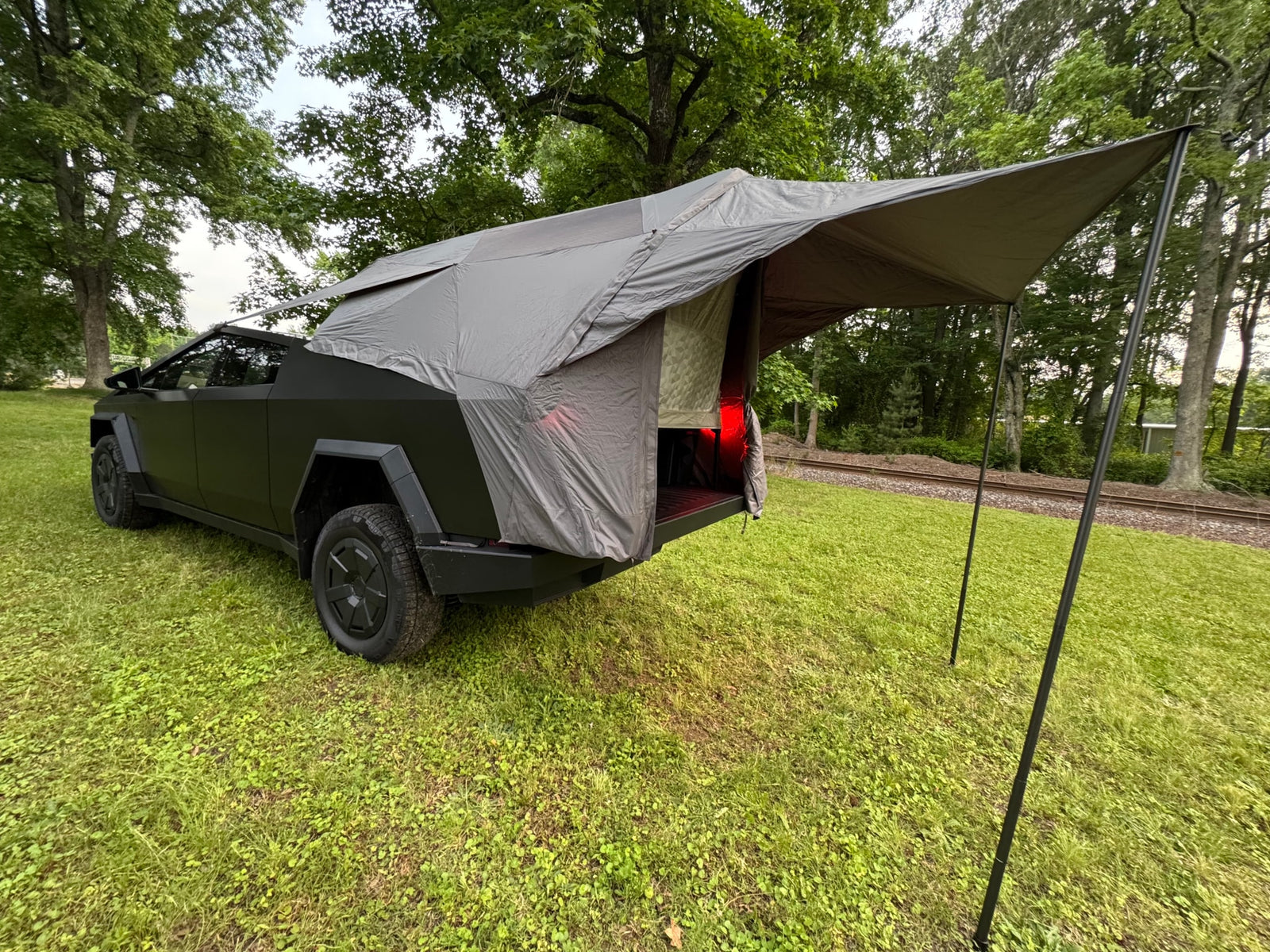  with a rear tent and awning in a grassy field.|Unique truck bed tent setup