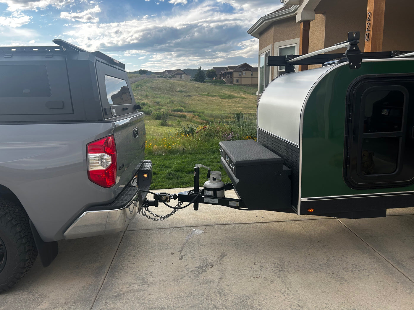 Grey pickup truck hitched to a green teardrop RV trailer, with a dog inside. An ideal RV rental for your next trip. — photo 3