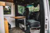 RV rental interior: Swivel front seats, adjustable table, and window offer comfort in this camper van.