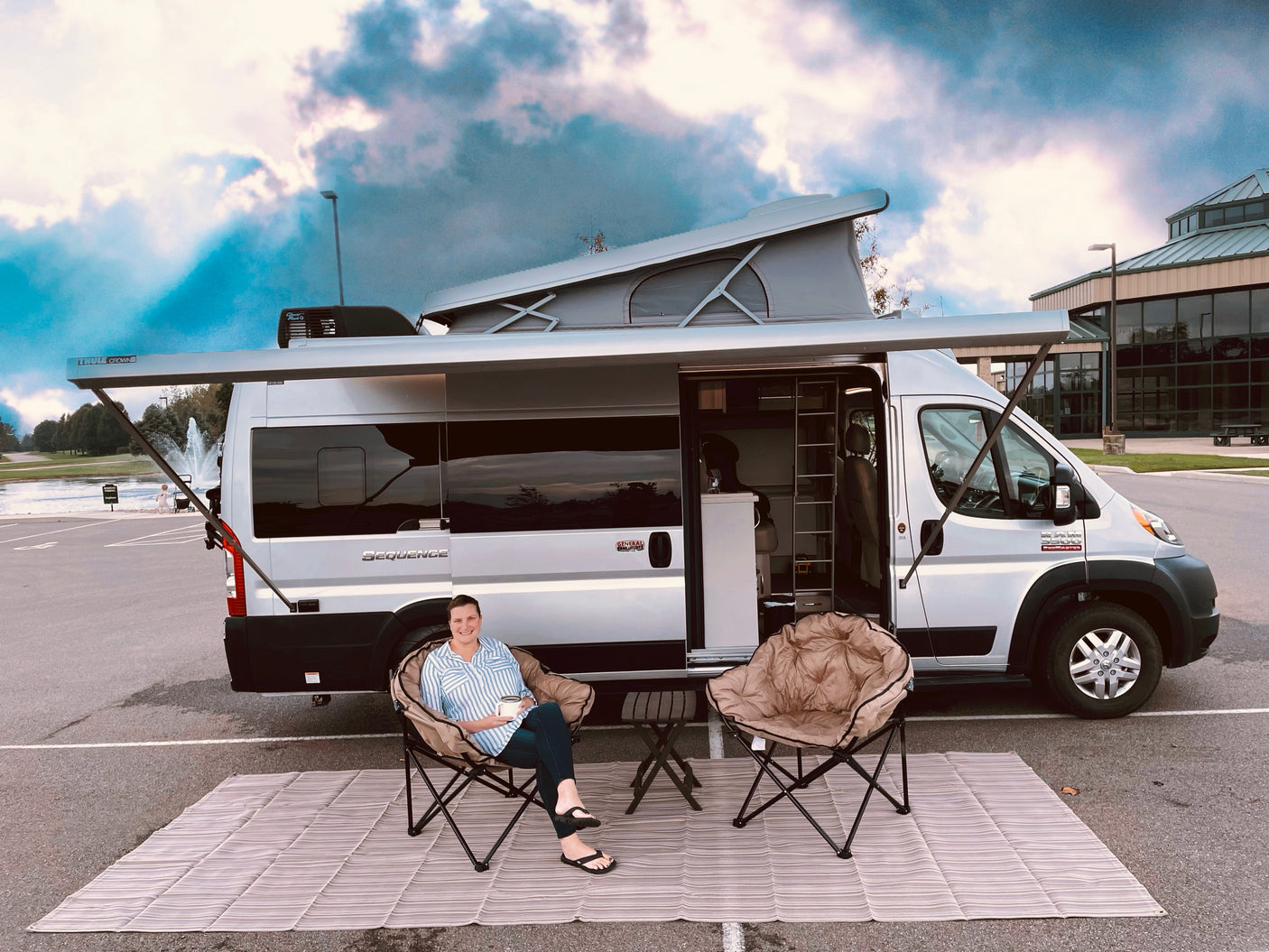 A cozy outdoor setup with a woman relaxing by her Ram Sequence **RV rental**, ready for comfortable road trip adventures.