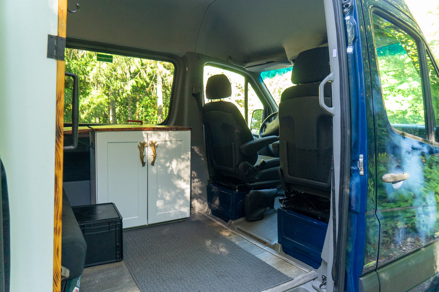 Inside a spacious RV rental, featuring a cozy kitchenette and front seats, ready for adventure amidst nature.