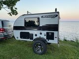 Compact Sundray Sport RV rental parked by a tranquil lake at dusk, ready for adventure. Tow vehicle present.