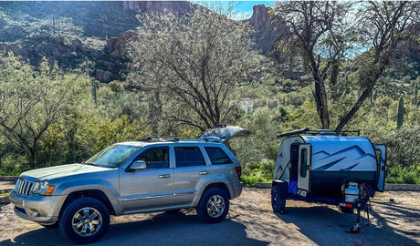 Explore the great outdoors with this RV rental setup: a silver Jeep SUV & teardrop camper in a desert landscape. Mountains visible. #rvrental