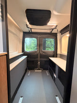 Spacious, modular camper van interior, ideal for an rv rental. Features side benches, storage, and rear windows.