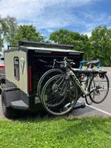 Rugged adventure trailer with two bikes, ready for an RV rental trip. Perfect for outdoor escapes under blue skies.