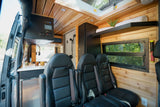 This modern RV rental showcases a bright interior with wood paneling, sleek kitchen, plush seating, and a compact shower.
