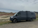 Adventure awaits! This gray camper van, perfect for an RV rental, explores colorful hills under an overcast sky.