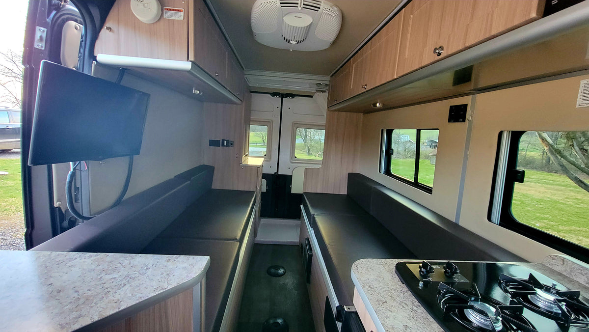 Spacious RV rental interior with convertible seating, kitchen, and TV. This camper van offers a comfortable living space for travel. — photo 10