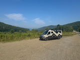 Explore nature with this unique RV rental van, parked by a scenic lake and mountains.