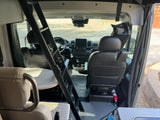 RV rental interior: Front cab, swivel seats, dashboard, and a ladder providing access to an upper sleeping area.