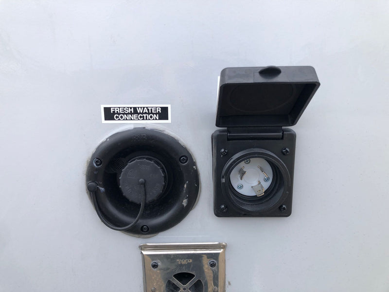 RV rental side showing fresh water connection, shore power electrical inlet, and furnace vent. — photo 8