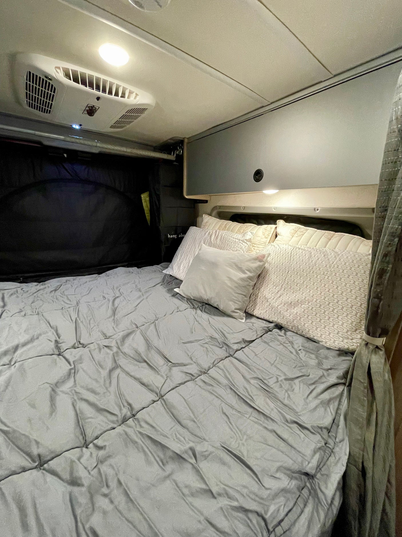 Cozy rv rental bedroom with a comfortable bed, overhead AC, and ambient lighting for a relaxing stay.