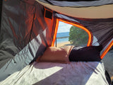 Serene beach camping from an RV rental. Inside, a cozy bed offers ocean views through the tent opening.