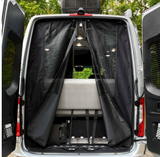 Open rear doors of an RV rental with a magnetic black mesh screen door partially open, revealing the bright interior and bench.