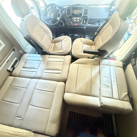 RV rental: Light tan interior showing front cockpit and rear flexible seating that converts to a bed in this campervan.