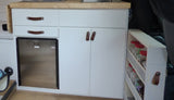 RV rental kitchen: compact white cabinets with leather pulls, built-in mini-fridge, and pull-out spice rack.