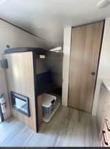RV rental interior featuring modern bunk beds, an electric fireplace, a storage bin, and a light-colored door.