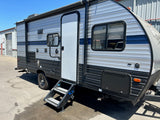 Bright gray and black rv rental, parked outdoors with its entry steps deployed and awning retracted, ready for adventure.