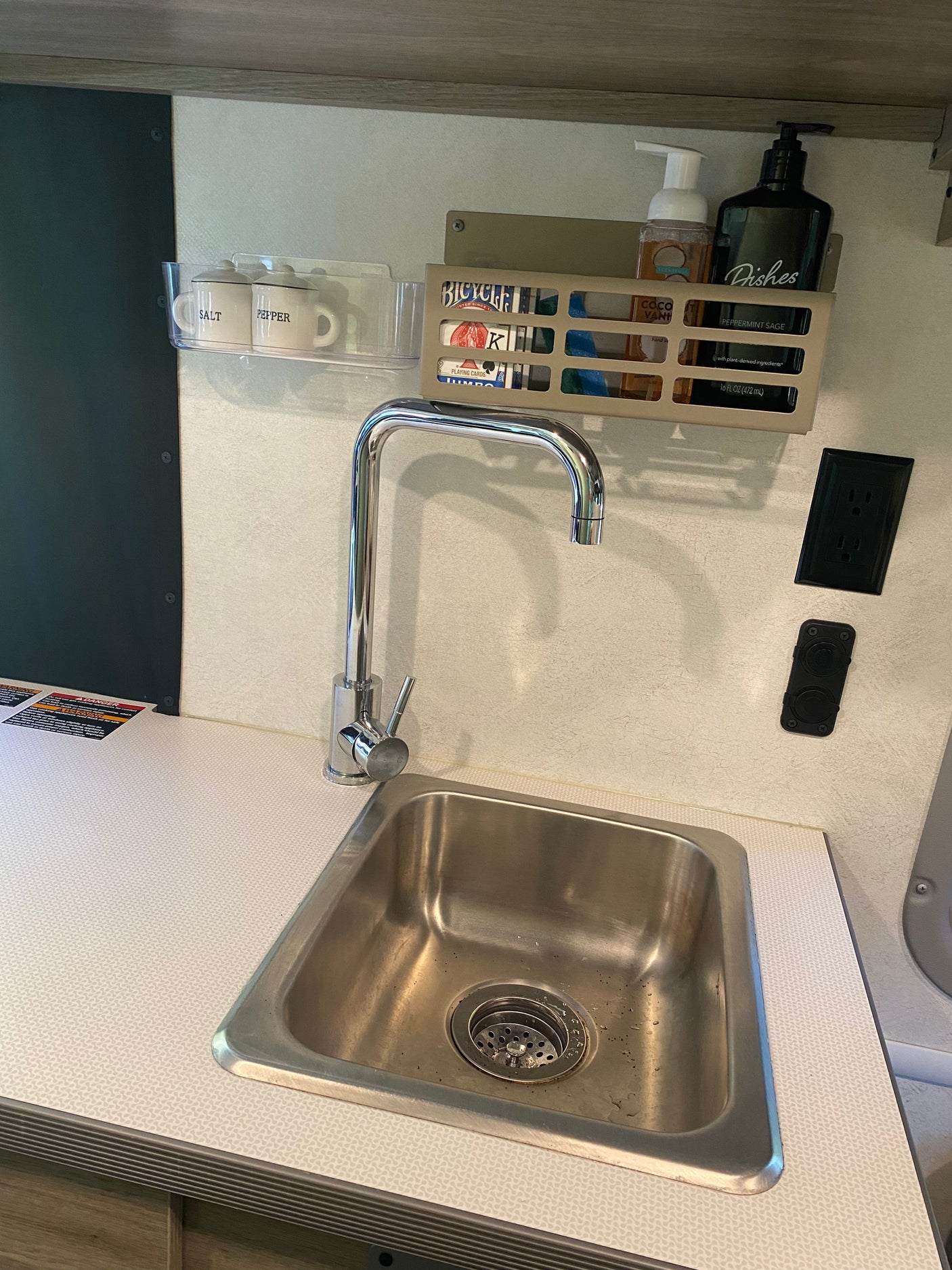 Organized RV rental kitchen sink with faucet, countertop, salt/pepper shakers, and soaps. Compact for travel.