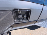 RV rental: Open utility panel on grey van showing water fill cap and other connections for camper services.