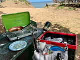 RV rental outdoor cooking by the beach: Portable stove, pan, and camping kitchen essentials organized on a picnic table.