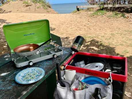 RV rental outdoor cooking by the beach: Portable stove, pan, and camping kitchen essentials organized on a picnic table.