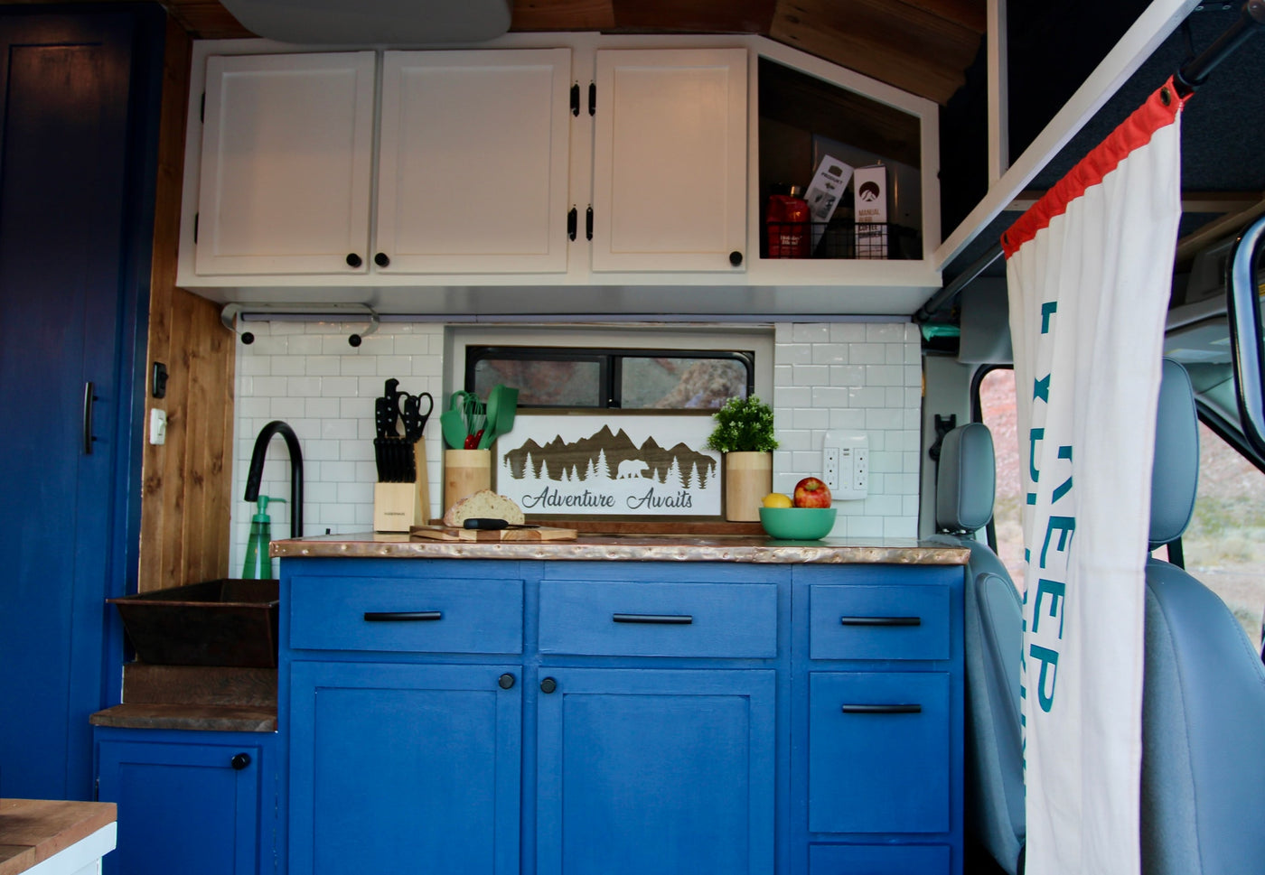 Step inside this RV rental's well-equipped kitchen, featuring vibrant blue cabinets, white backsplash, and a sink. — photo 10