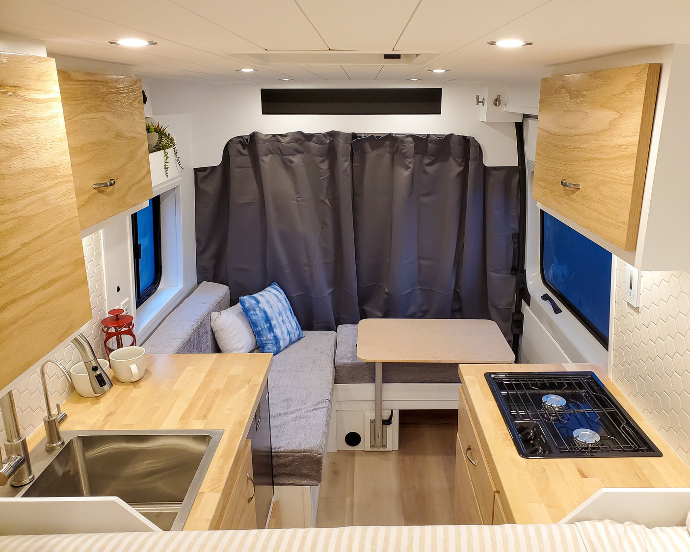 Inside this cozy RV rental: compact kitchen with sink/stove, dinette seating, and smart storage for your adventure.