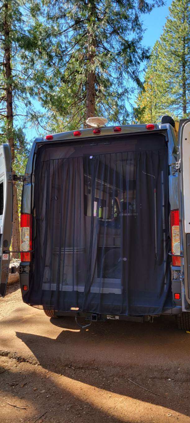 Rear view of an RV rental with an open bug screen, parked in a sunny forest. Perfect for outdoor adventures. — photo 11