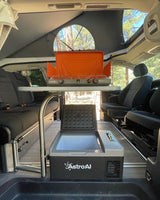 Inside an RV rental pop-top van: GSI stove, AstroAI cooler, & convertible seating for outdoor cooking & camping.